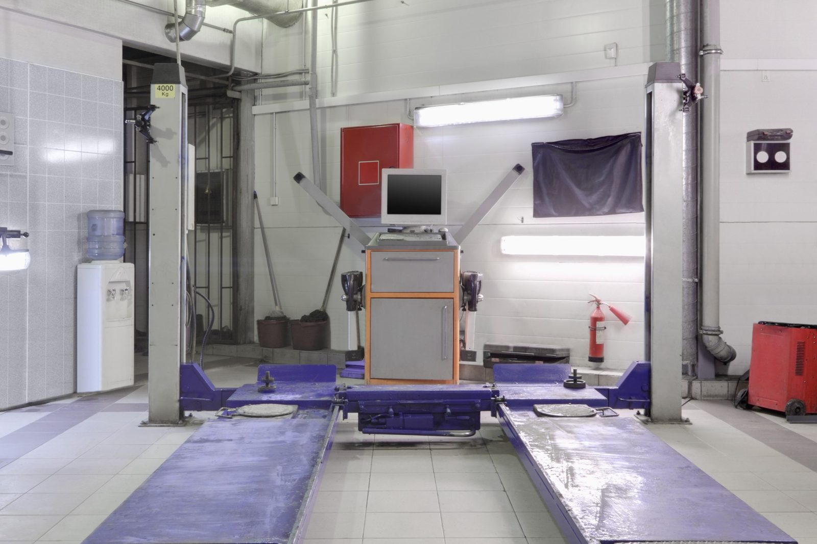 Glossy light-gray epoxy floor reflecting blue car lifts in a clean automotive shop